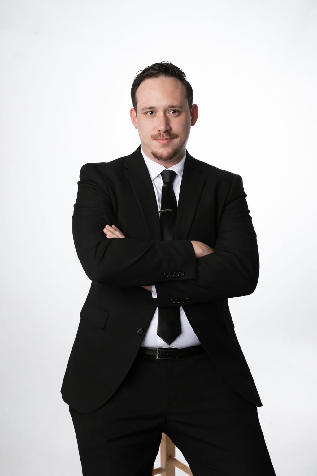 DJ Drew Segura in a black suit, arms crossed