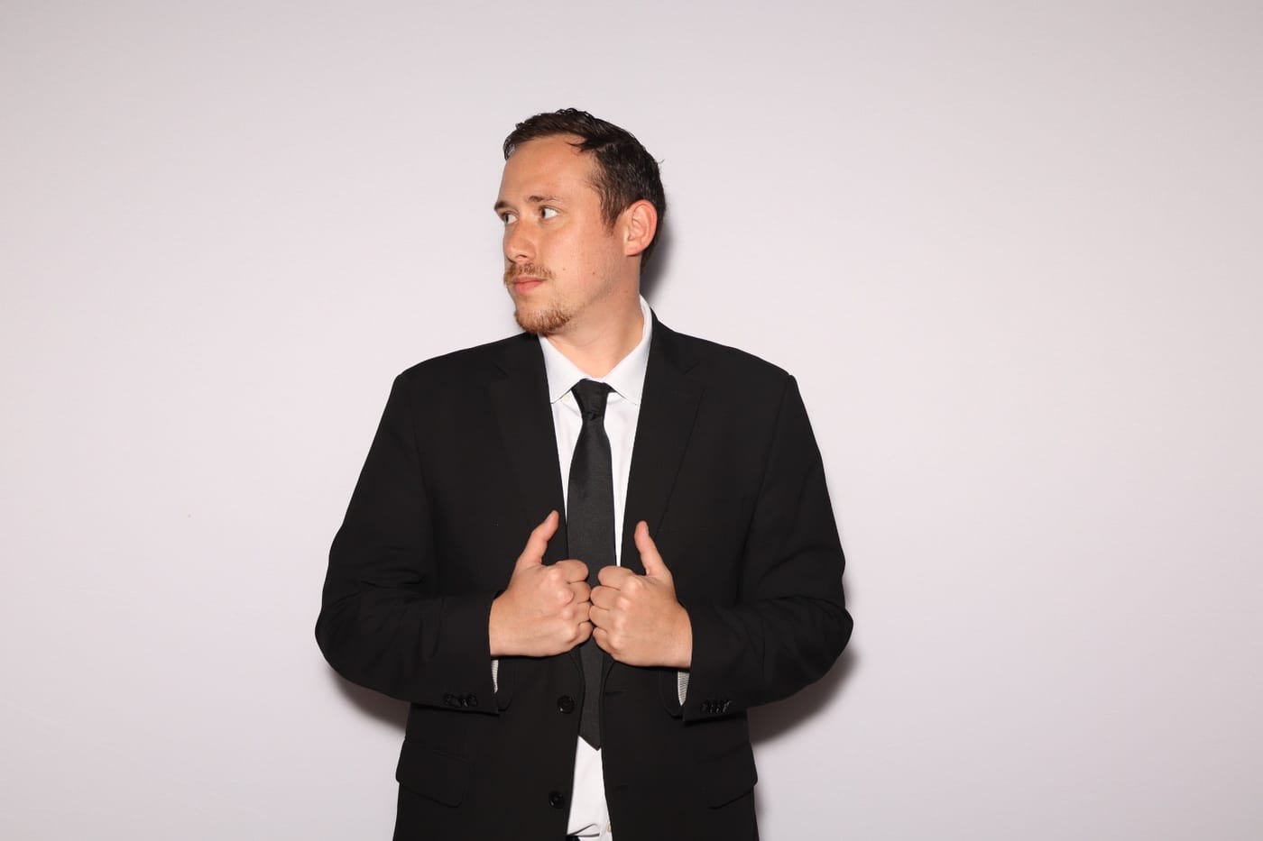 Drew in a black suit, adjusting his jacket