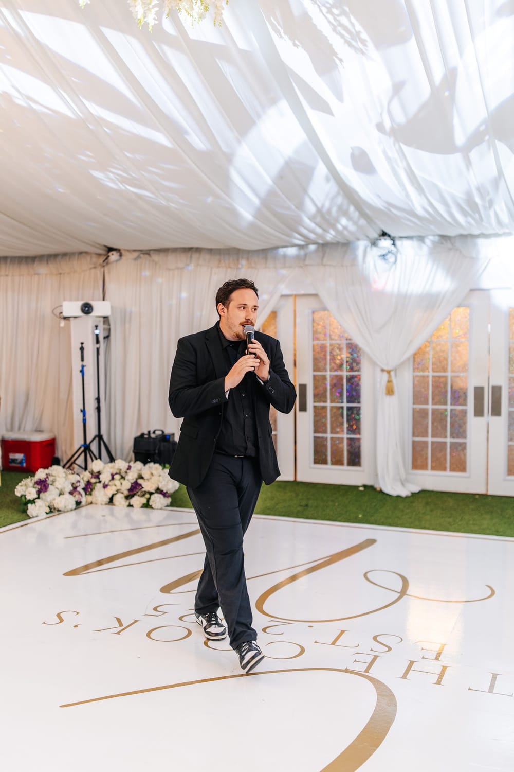 Drew on the mic walking across a monogrammed wedding dance floor