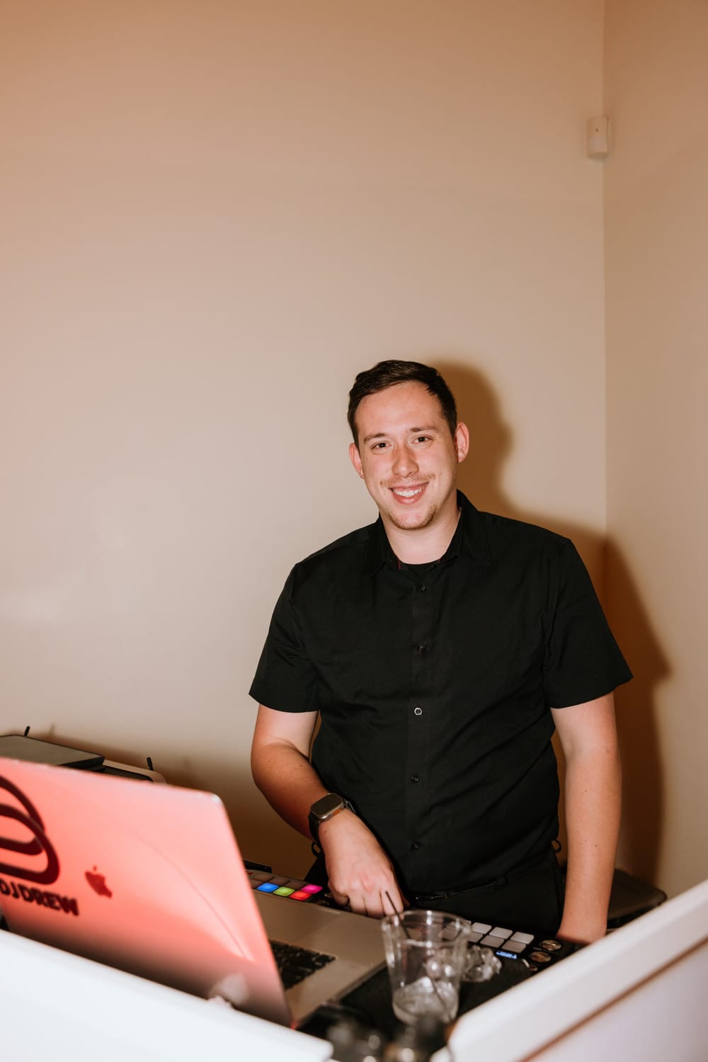 Drew smiling behind the decks at a wedding